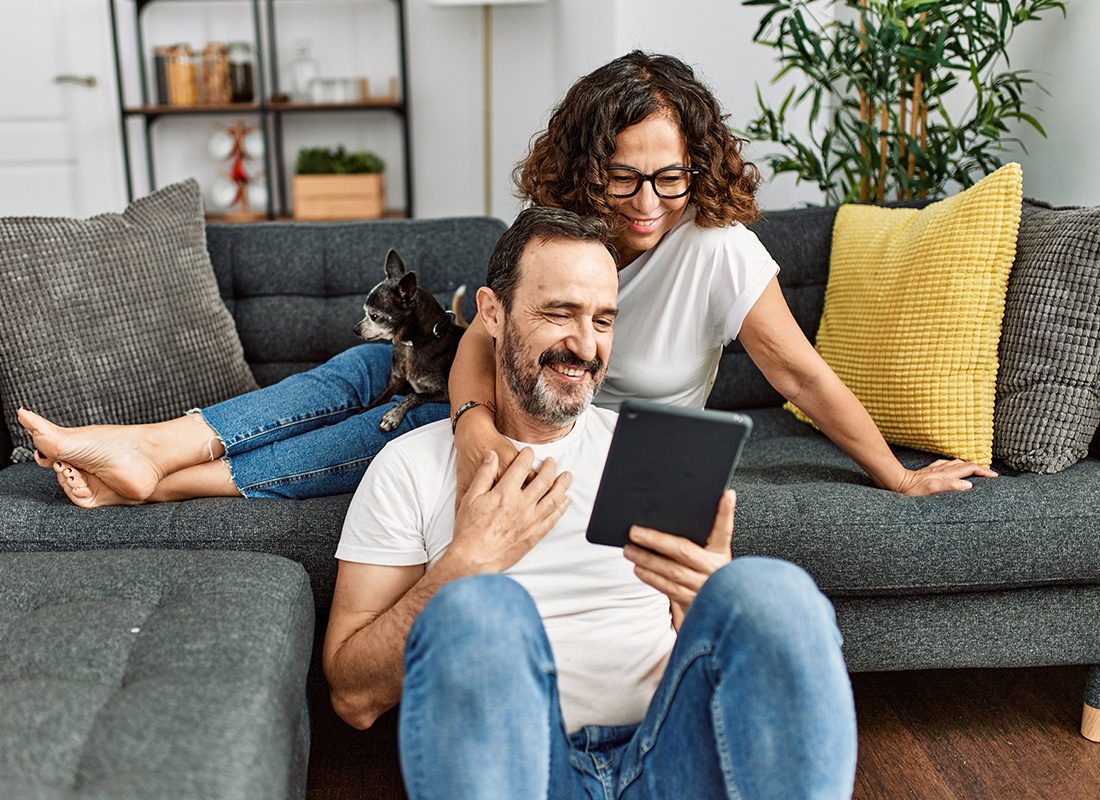 Contact - Happy Couple With Their Dog Sit Together on a Sofa Using a Tablet