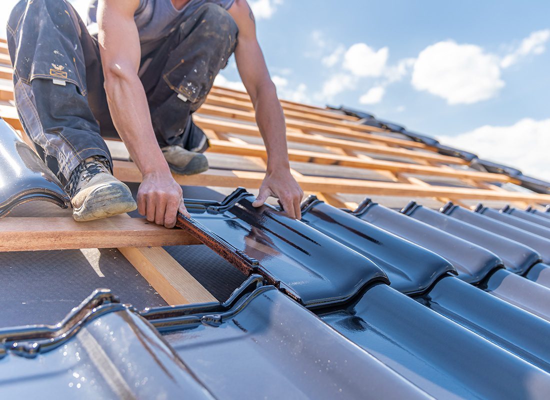 Insurance by Industry - Construction Work on Roof Laying Down Shingles on a Sunny Day